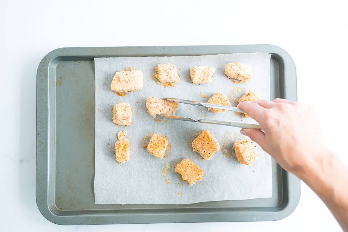 Salon nuggets being turned with tongs half way through cooking