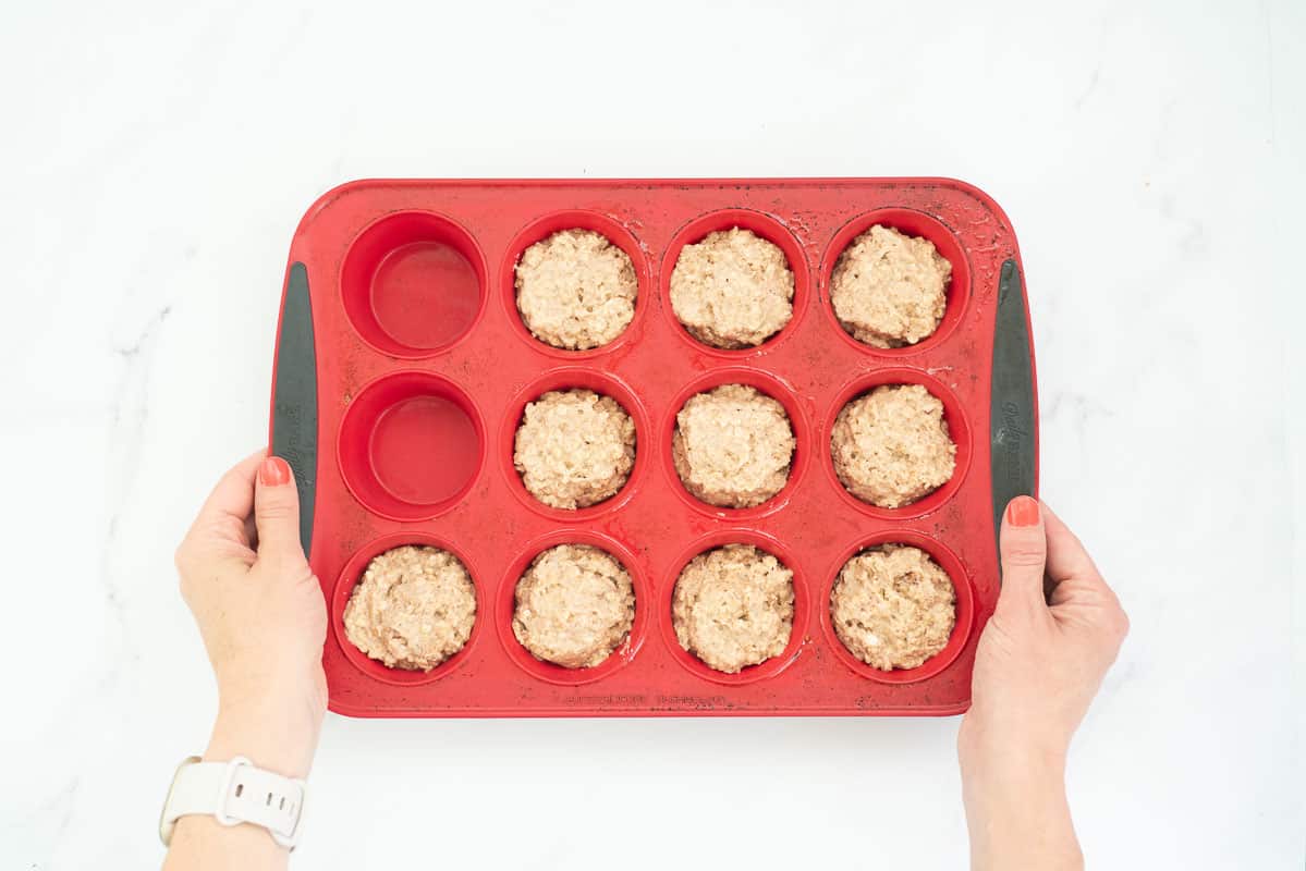 Muffin batter portioned into 10 of 12 cups in a red silicone muffin pan.