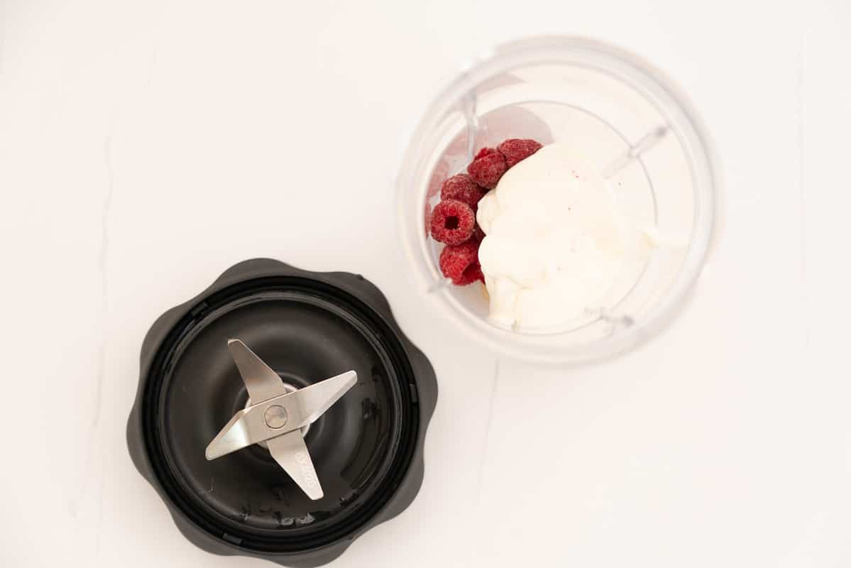 Yogurt, raspberries and pears in a blender ready to be puréed.