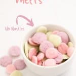 a small white bowl of baby yogurt melts in 3 colours, pale pink, lavender and pale green with text overlay.