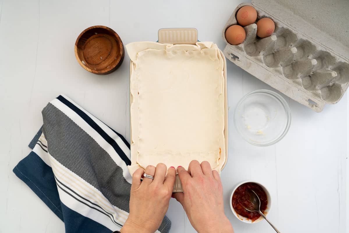 Woman's hand rolling and folding the edges of a pie.