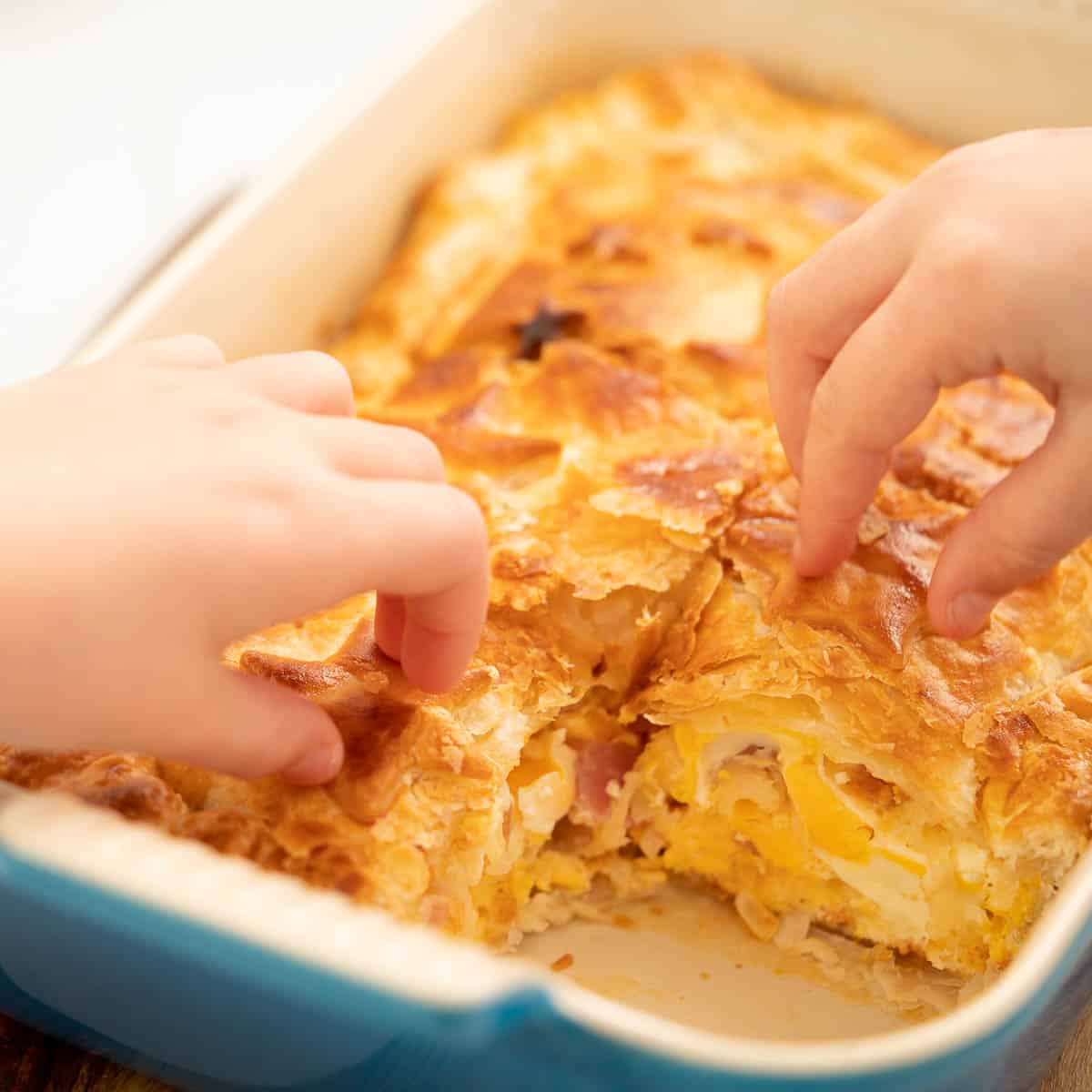 Children's hands picking off pastry stars from the top of a pie.