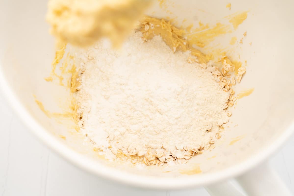 Flour, baking powder and rolled oats on top of creamed butter and sugar.