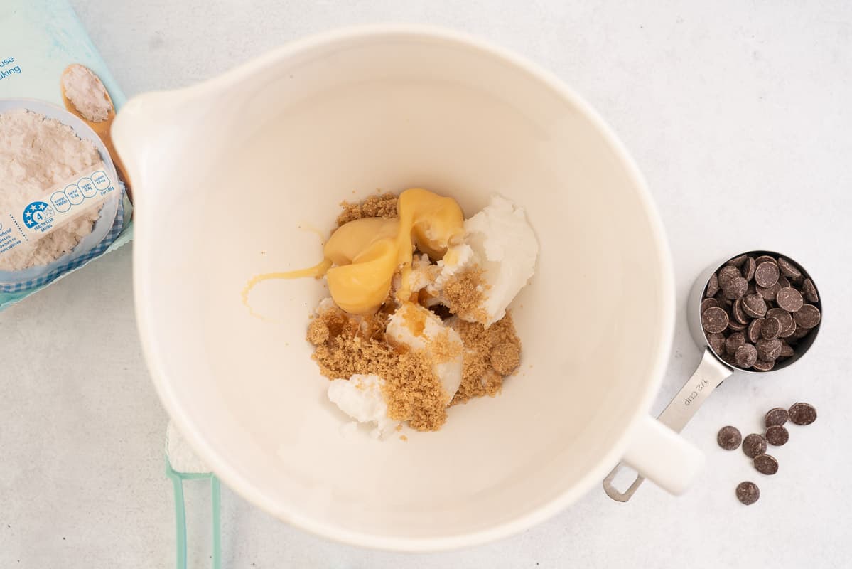 White ceramic mixing jug with coconut condensed milk, coconut oil and brown sugar.