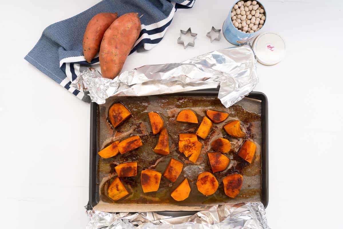 Roasted and caramelised chunks of kumara in a roasting tray.