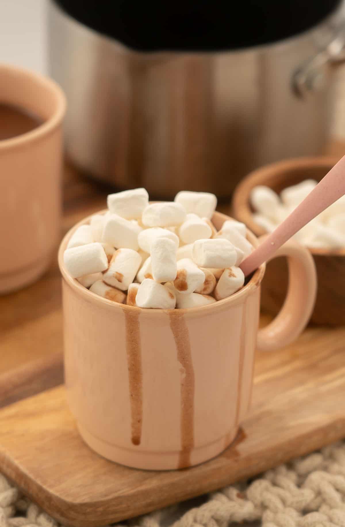 A pink mug of hot chocolate topped with mini marshmallows.