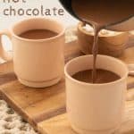 Hot chocolate being poured from a saucepan into a pink mug, with text overlay.