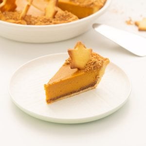 A slice of sweet potato pie decporated with a pastry star on a white plate.