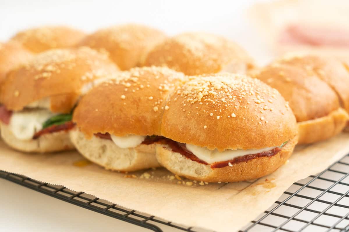 Toasted sliders filled with salami melted mozzarella and spinach leaves.