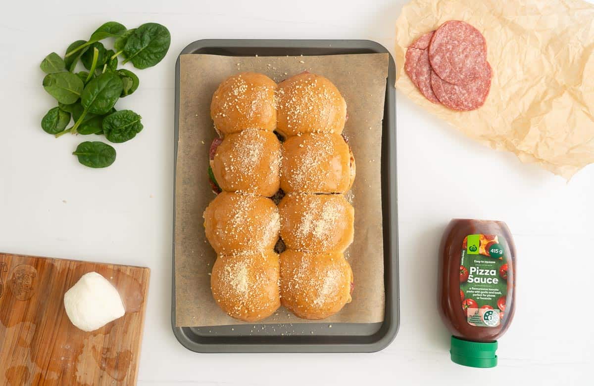 Eight small buns on a baking paper lined tray dusted with parmesan.