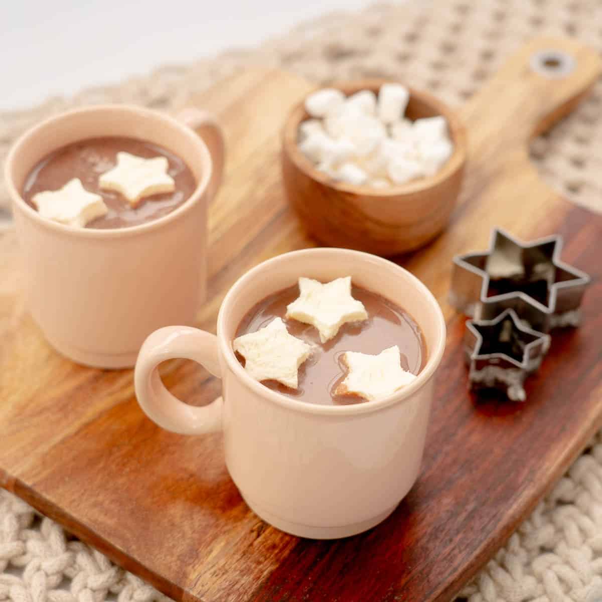 Two mugs of hot chocolate with floating star-shaped hot chocolate toppers