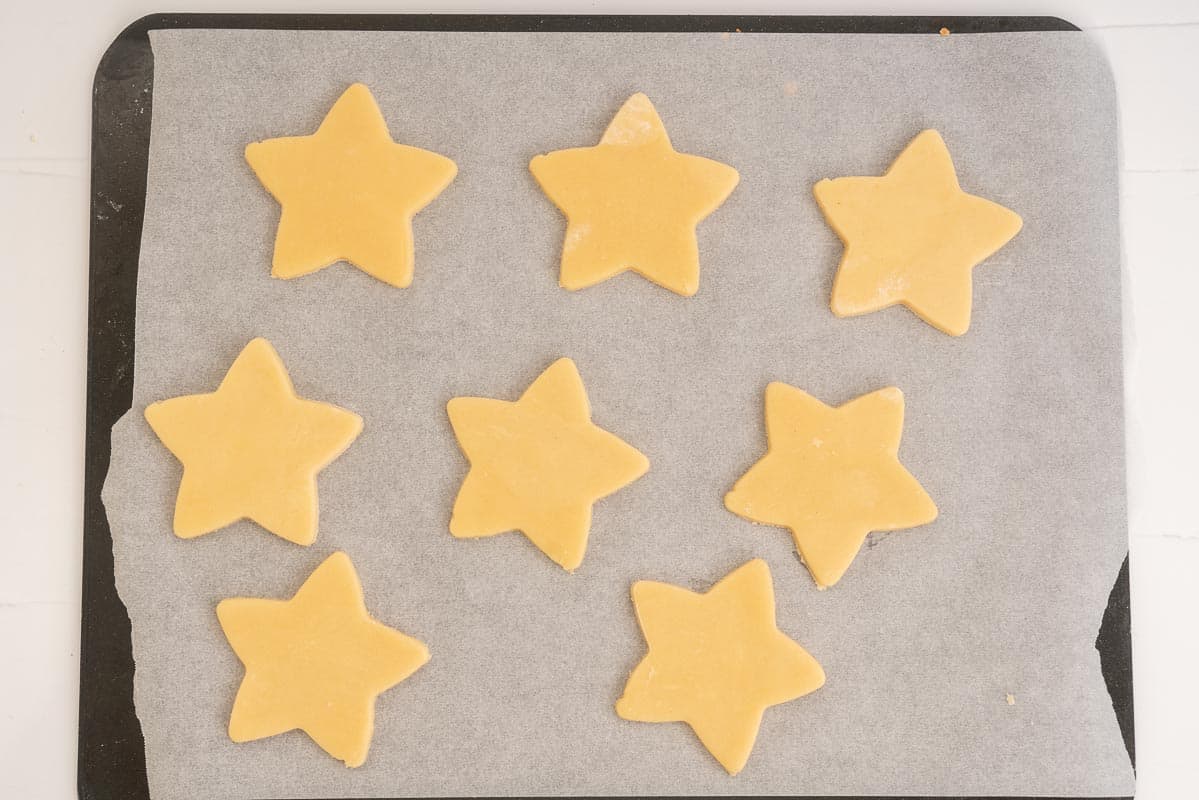 star shaped cookies on a baking-paper lined tray ready to be baked.