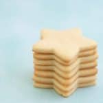 Seven star shaped sugar cookies stacked in a tower on a mint green background