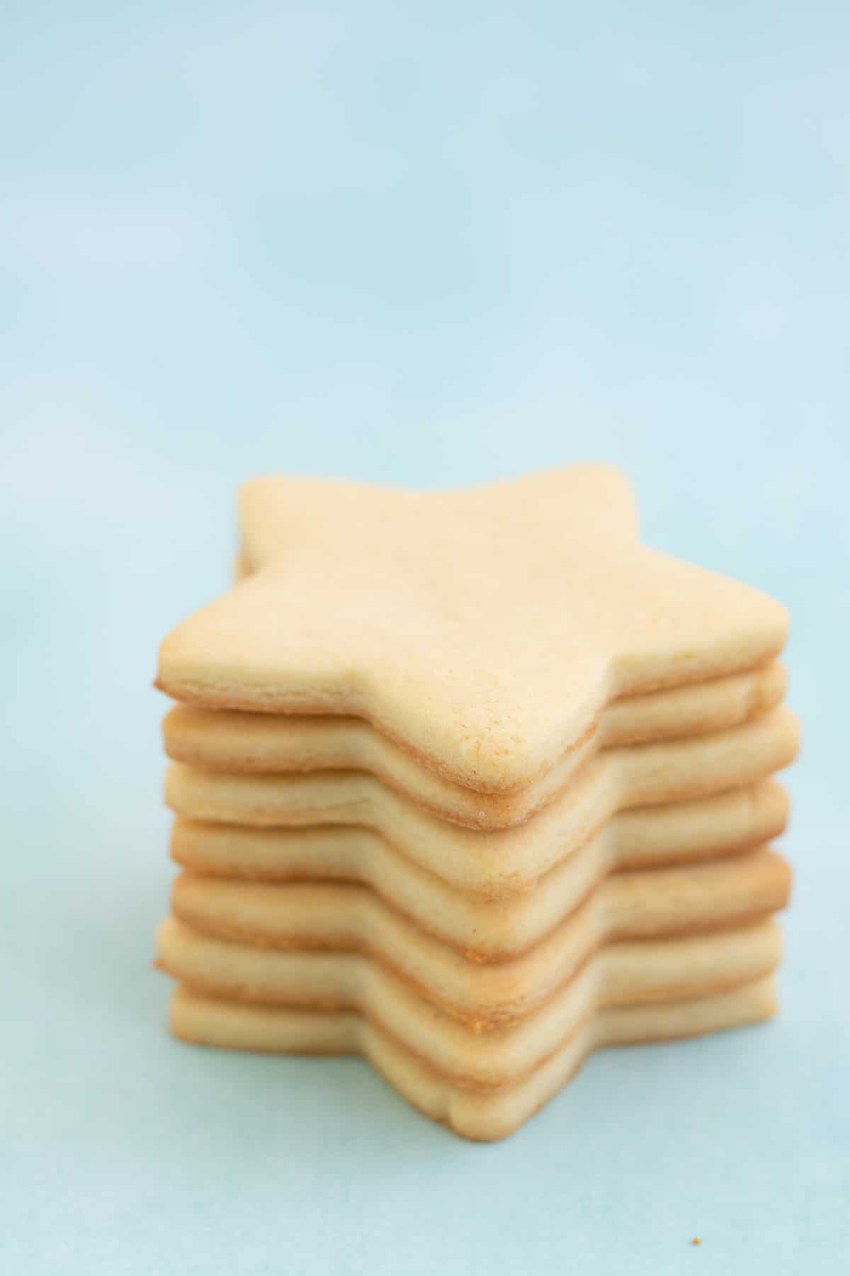 Seven star shaped sugar cookies stacked in a tower on a mint green background.