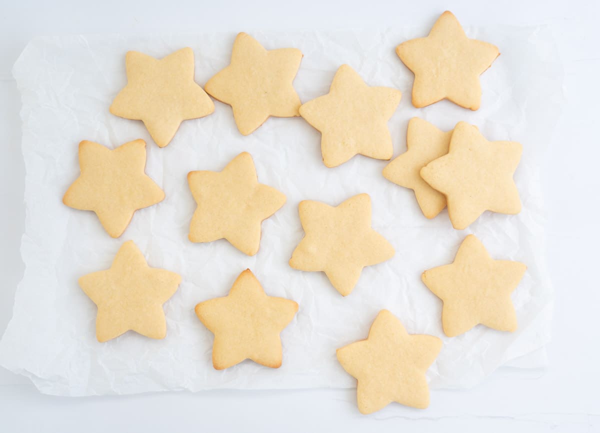 Thirteen star shaped cookies laid out on a piece of crumpled baking paper.