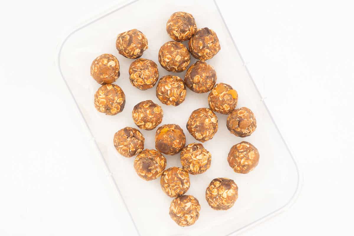 20 apricot oat balls in a container ready to refrigerate.
