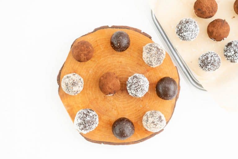 A selection of chocolate date balls presented on a rustic wooden slab.