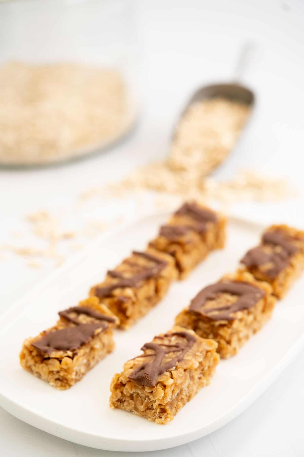 6 chocolate drizzled peanut butter bars on a white platter.