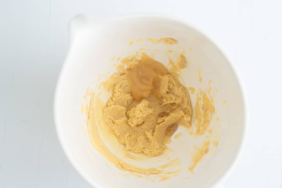 Creamed butter and sugar in a large mixing bowl with a spoonful of apple sauce ready to be beaten in.