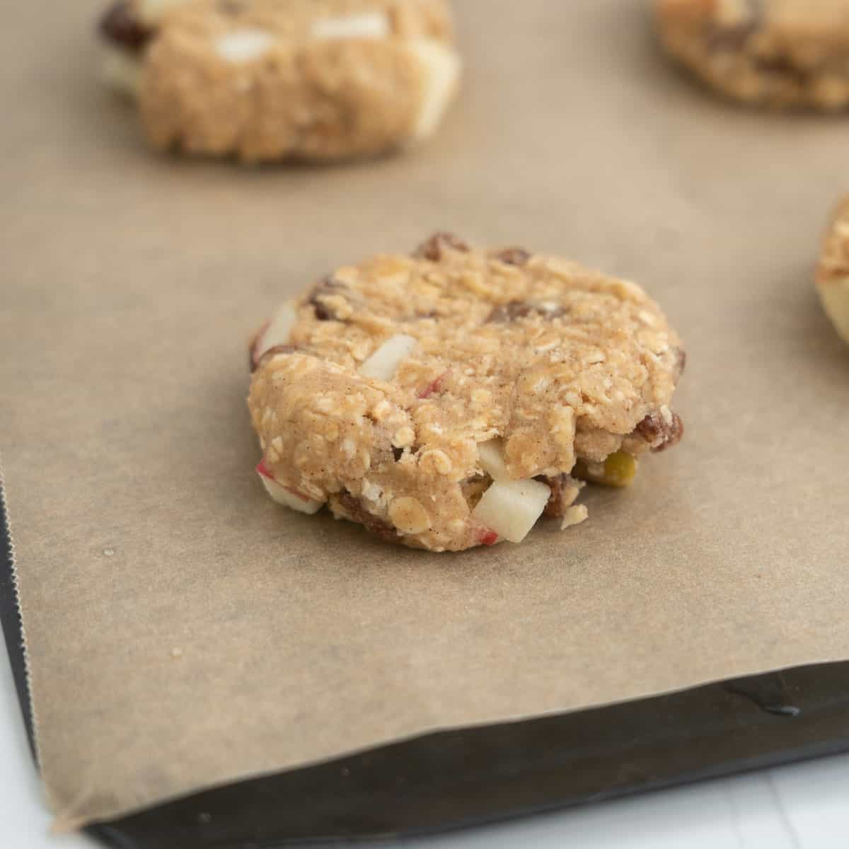 Close up of an apple cookie on a lined baking tray ready to go in the oven.