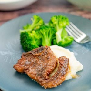 A sticky lamb chop on a bed of mashed potatoes and a side of steamed broccoli.