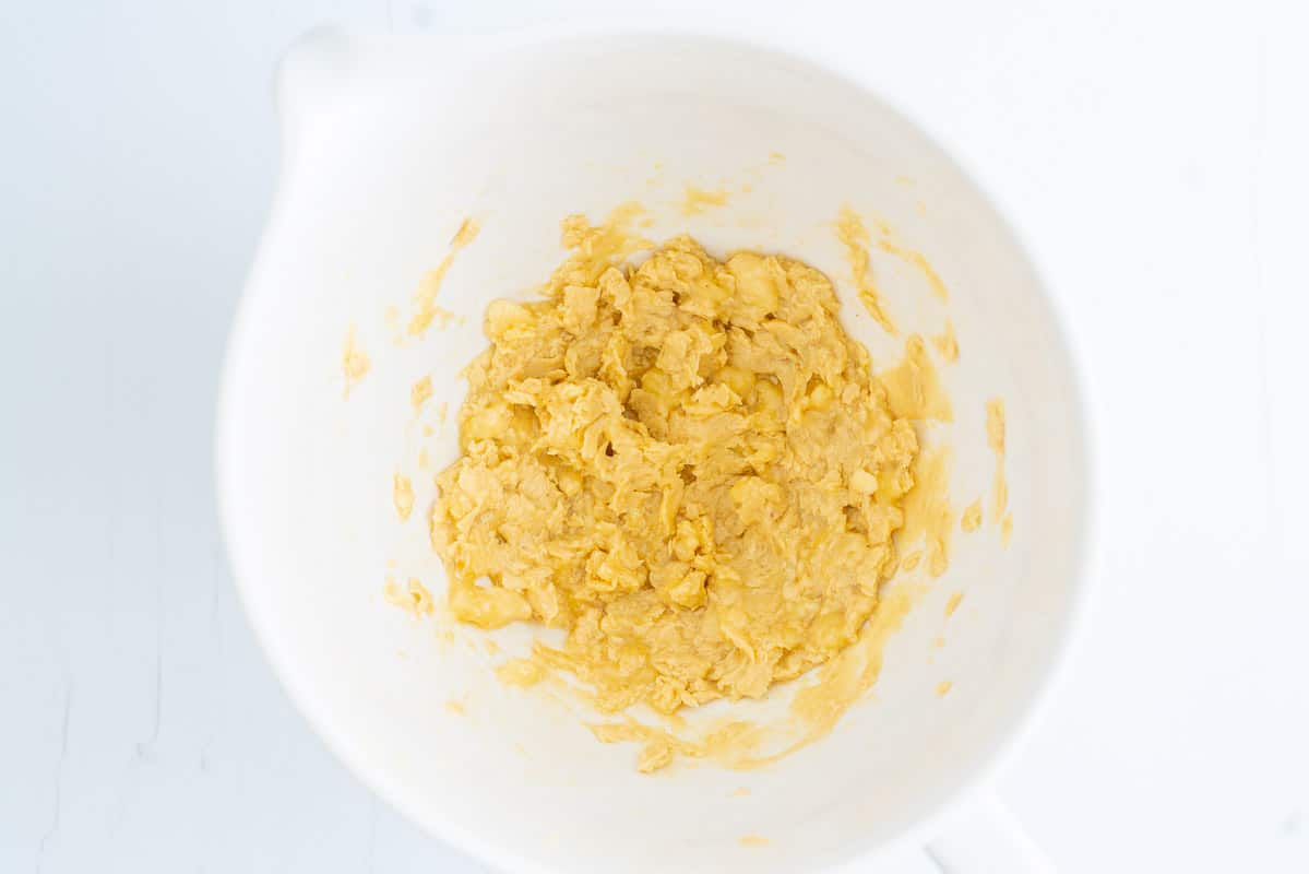 Butter, sugar and banana beaten in a white ceramic mixing bowl.