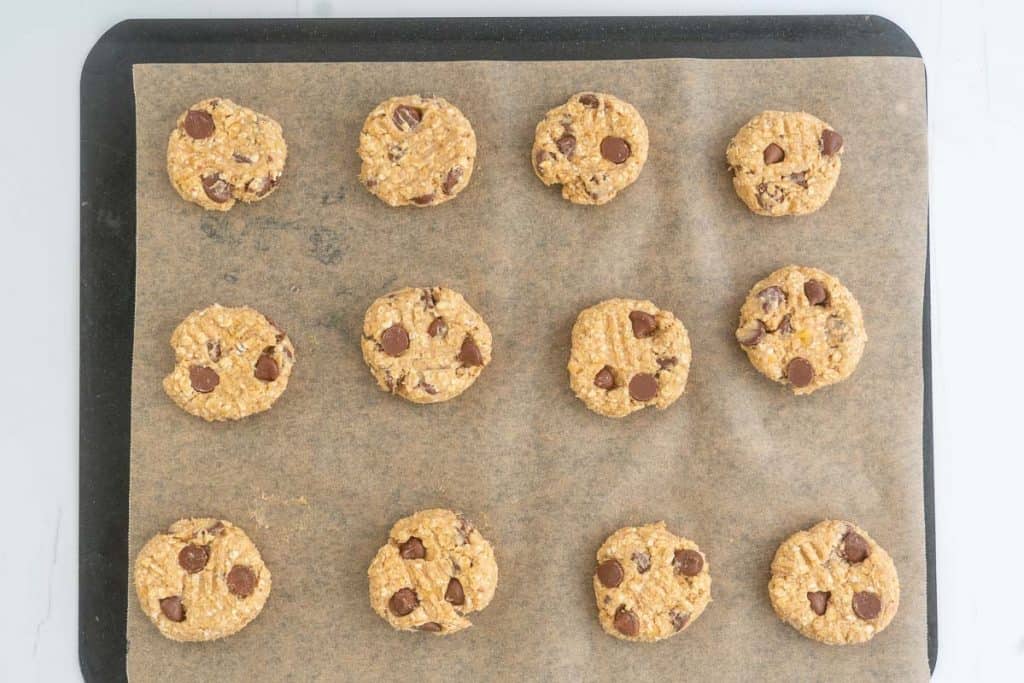 Banana oatmeal cookies ready on a lined baking tray ready to be baked,