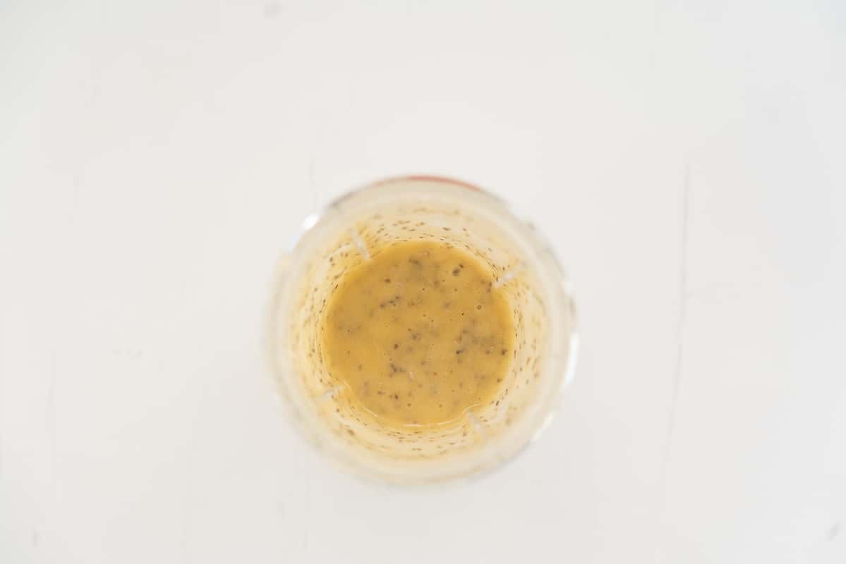 A blender cup filled woth blended banana and apple, chia seeds also visible.