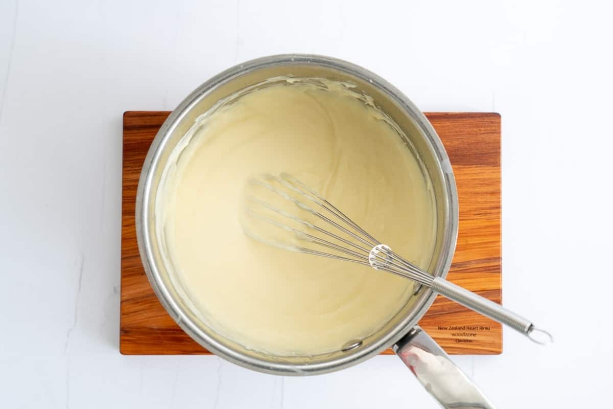 A saucepan of smooth cheese sauce.