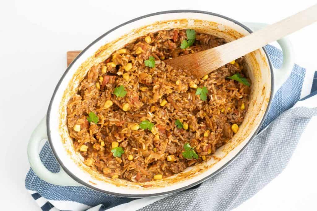 A dutch oven filled with Mexican mince and rice garnished with coriander leaves.