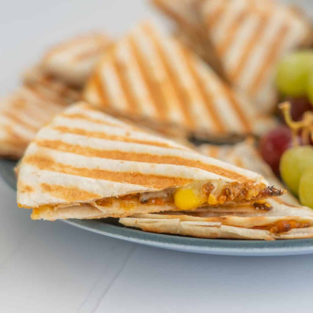A platter of quesadilla filled with mince, rice, corn and cheese.