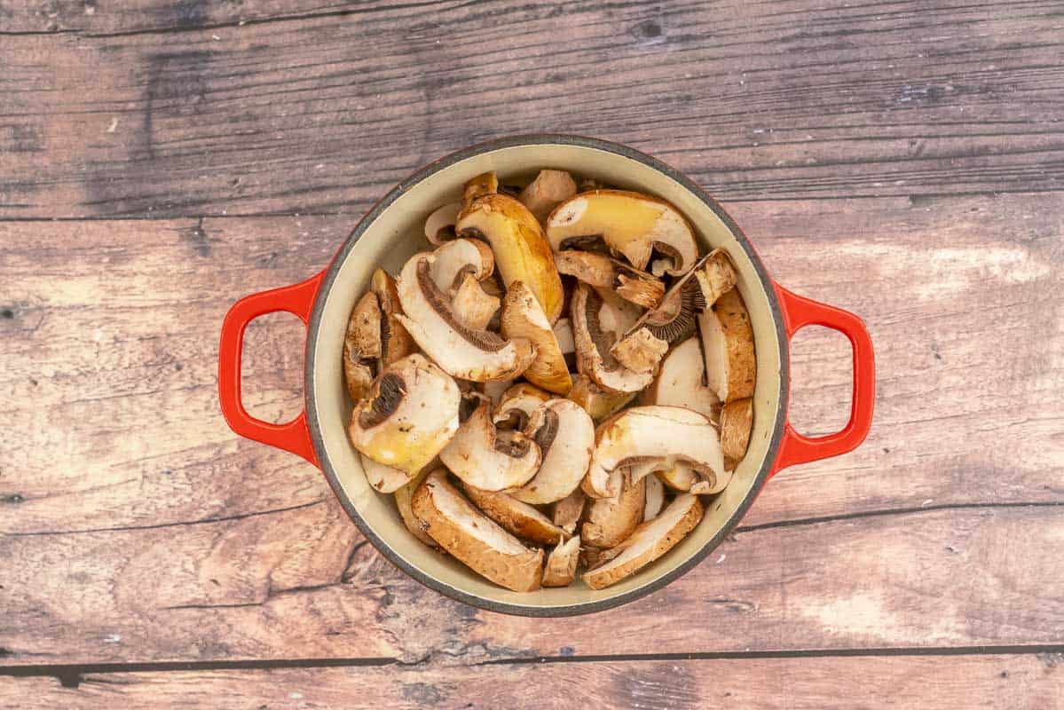 Sliced portobello mushrooms, drizzled with olive oil in a red baking dish.