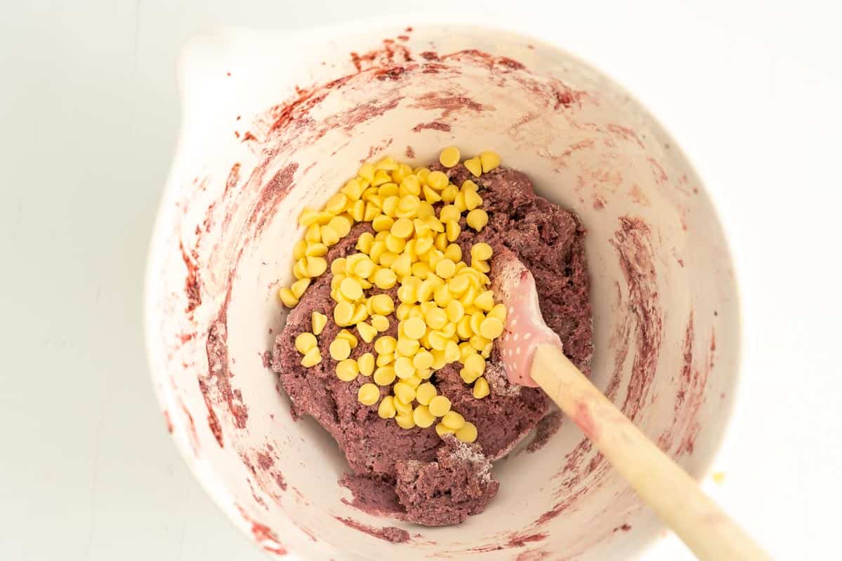 Purple cookie dough and white chocolate drops in a large mixing bowl.