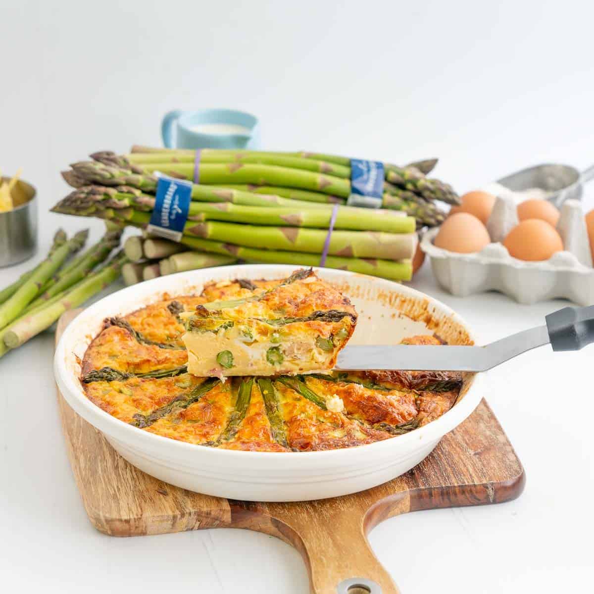 A slice of quiche on a serving spatula sitting on top of the remaining quiche,