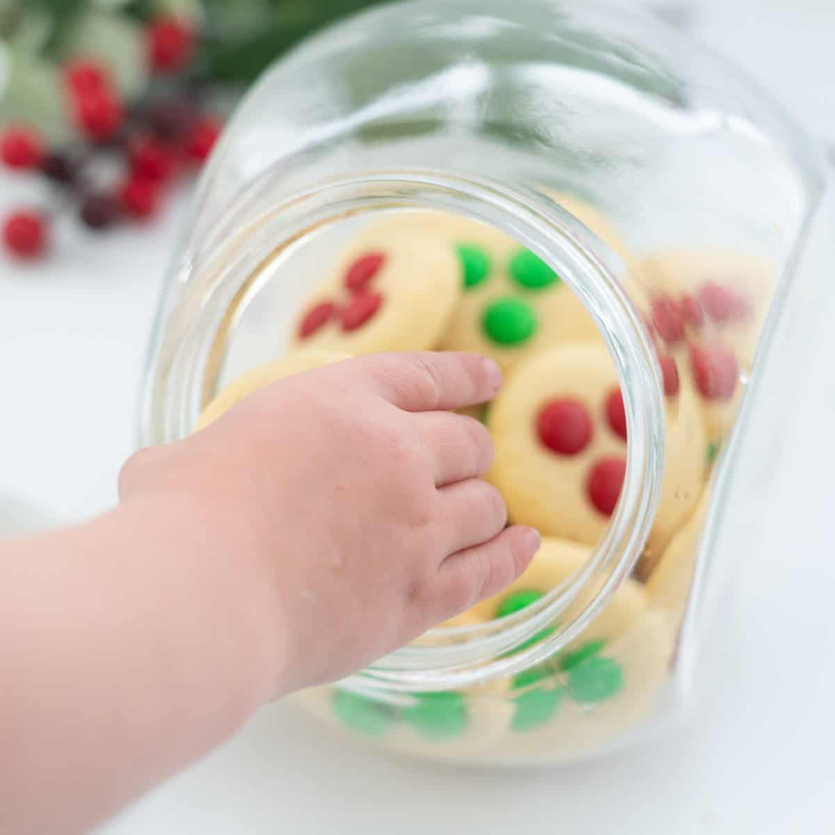 A child's hand reaching to get a cookie out of a cookie jar