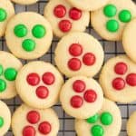 Cookies decorated with green and red m and m's on a cooling rack.
