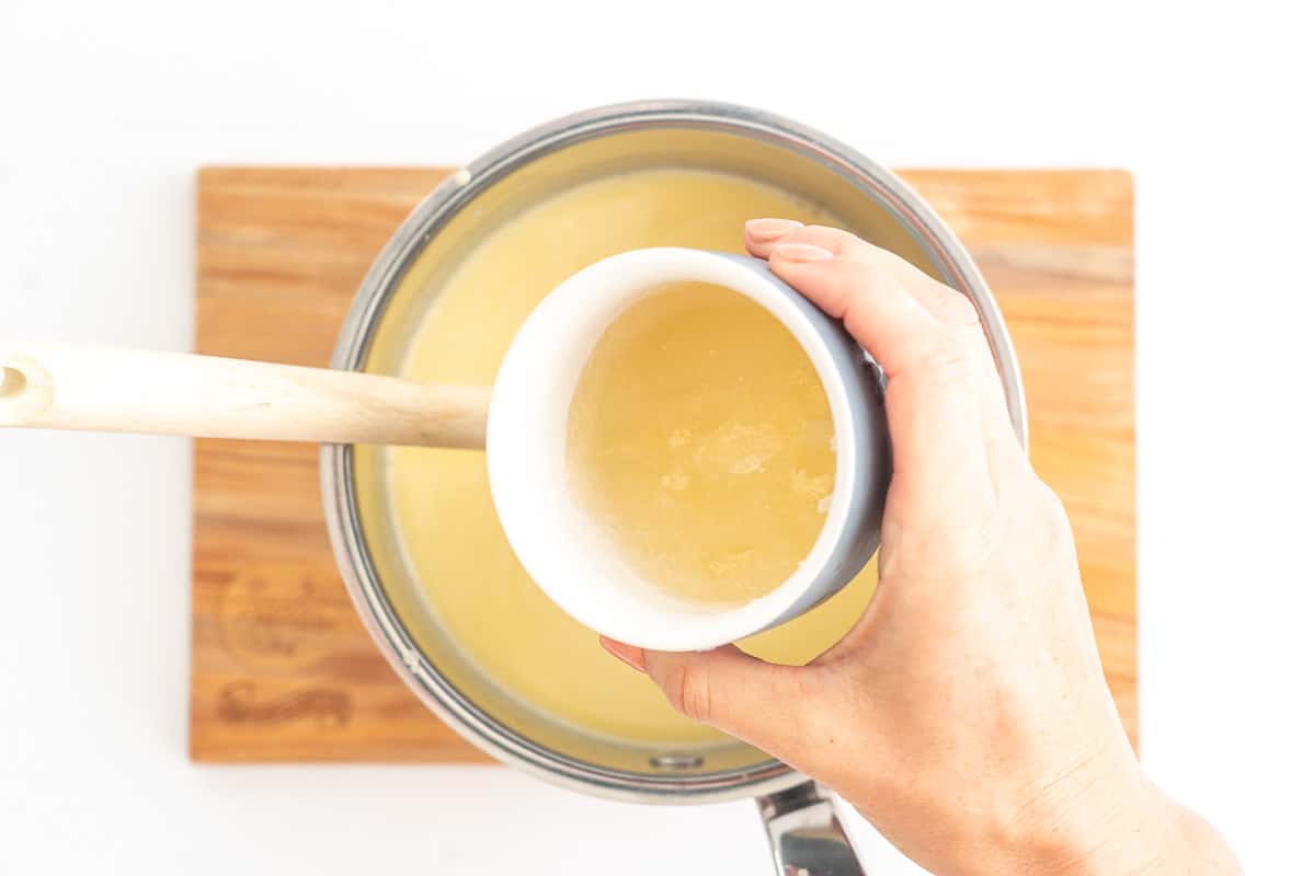 Softened gelatine being added to a saucepan of warmed cream.