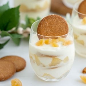 A layered dessert of yogurt, pears and ginger nut biscuits in a glass.