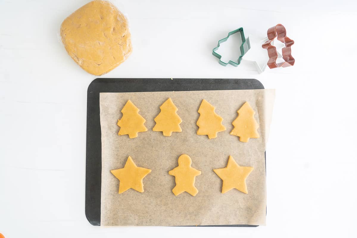 Uncooked gingerbread cookies on a baking paper lined tray ready to go into the oven.