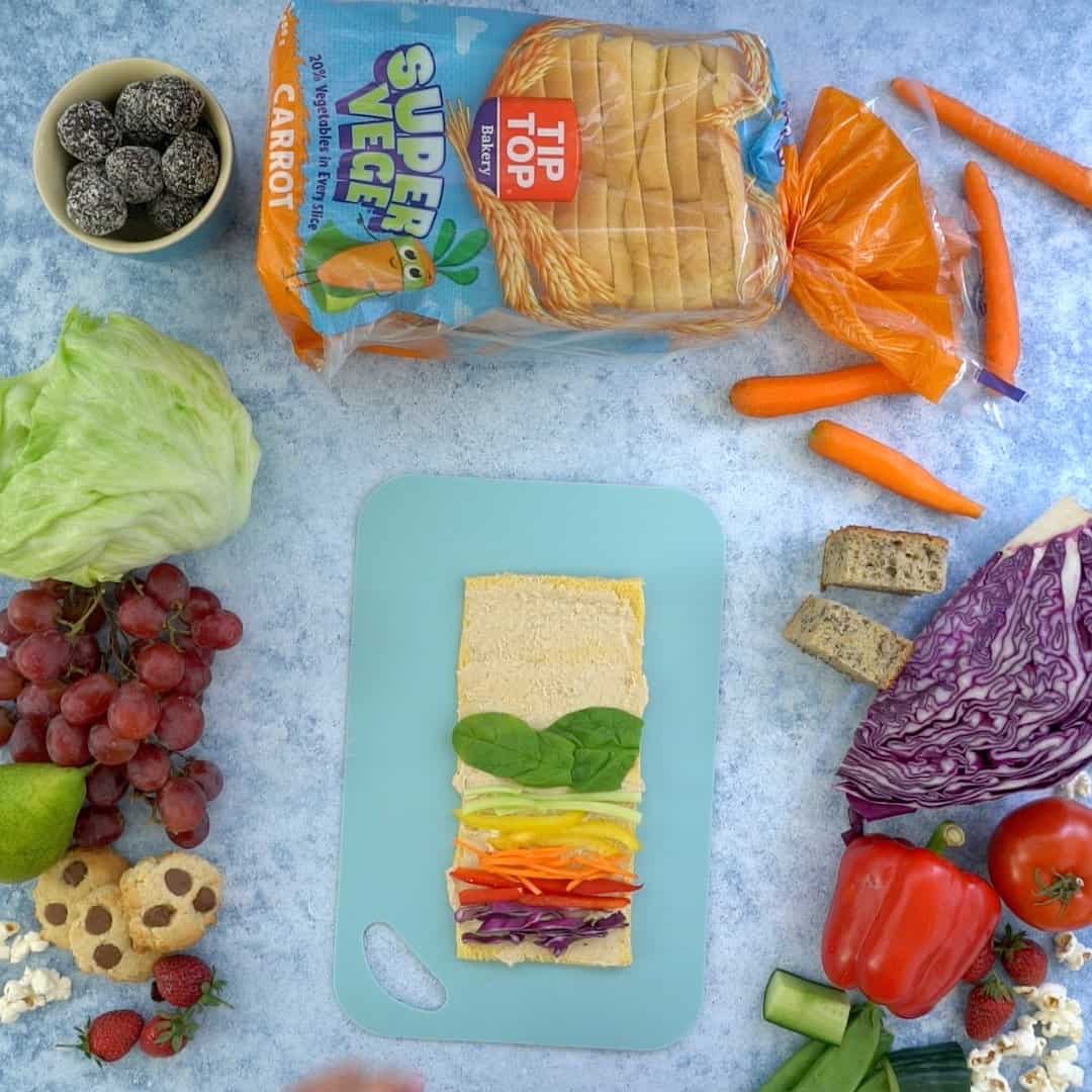 Colourful vegetables laid out as a rainbow ready to be rolled into a pinwheel sandwich.