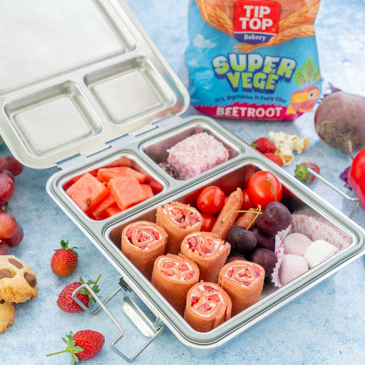 A stainless steel lunchbox packed with pink and red foods for Valentines day.