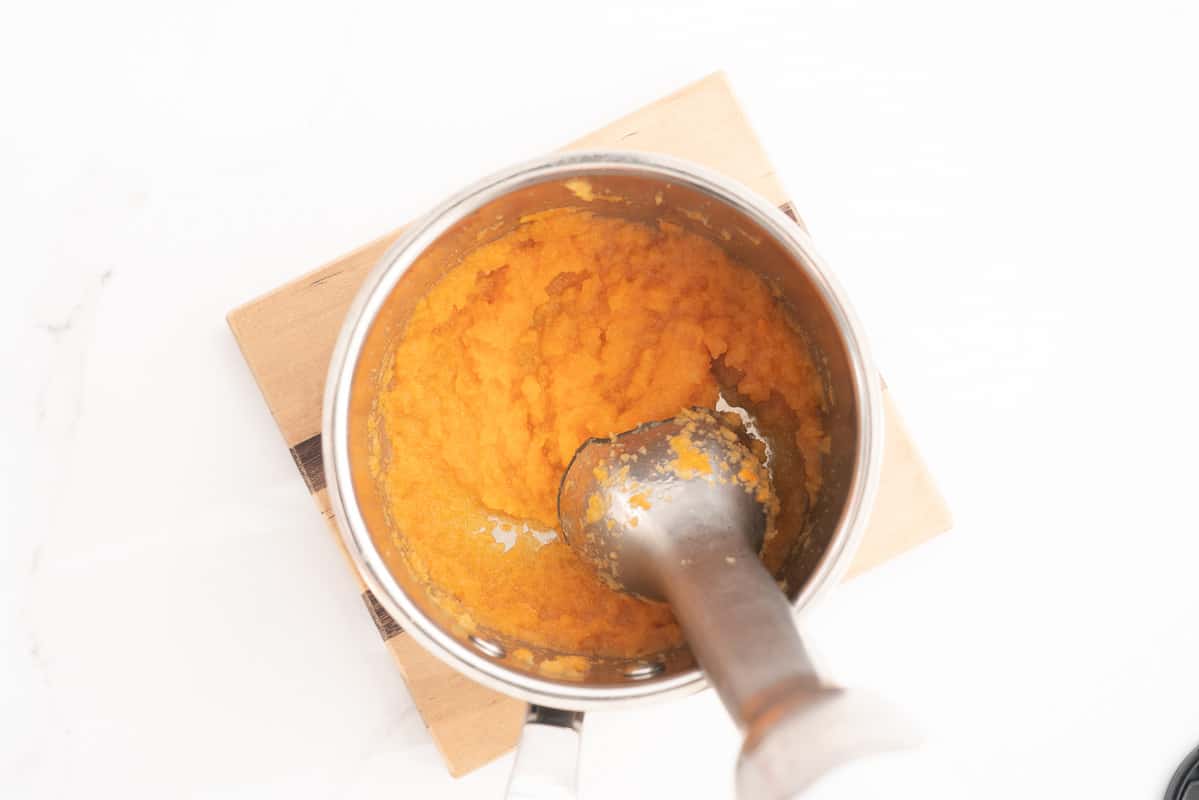 A stick blender puréeing apple and carrot