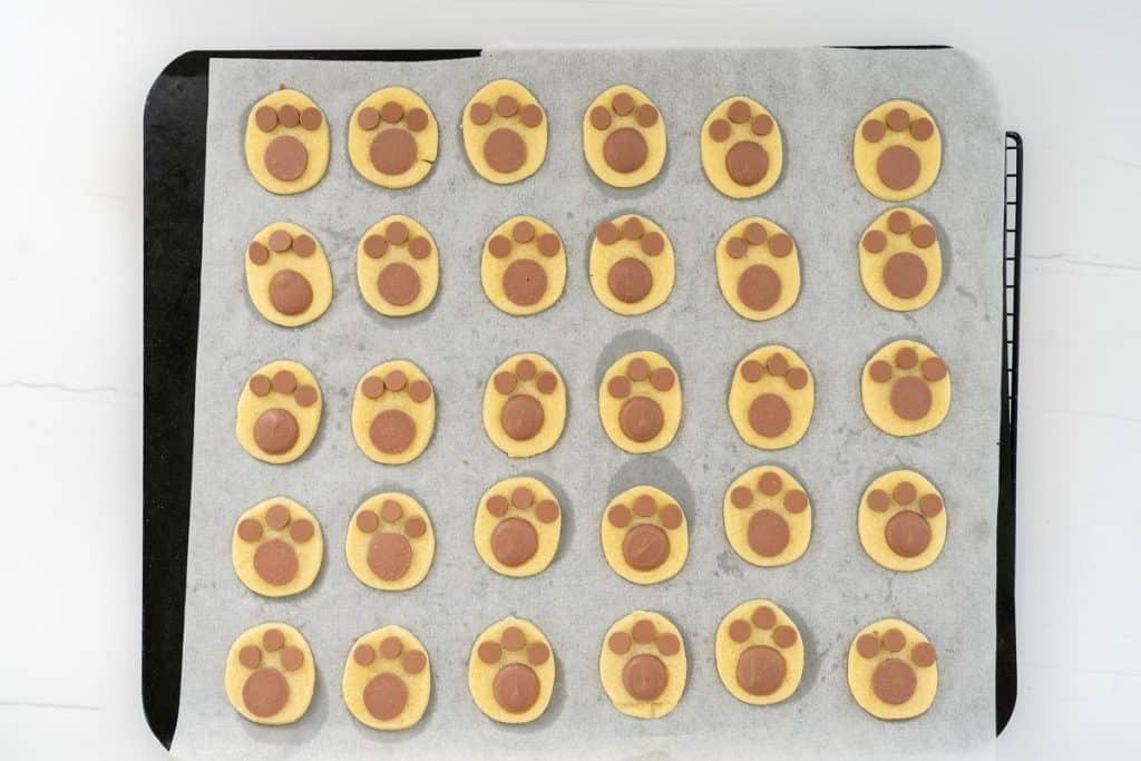 Baked footprint cookies on a lined cookie sheet.