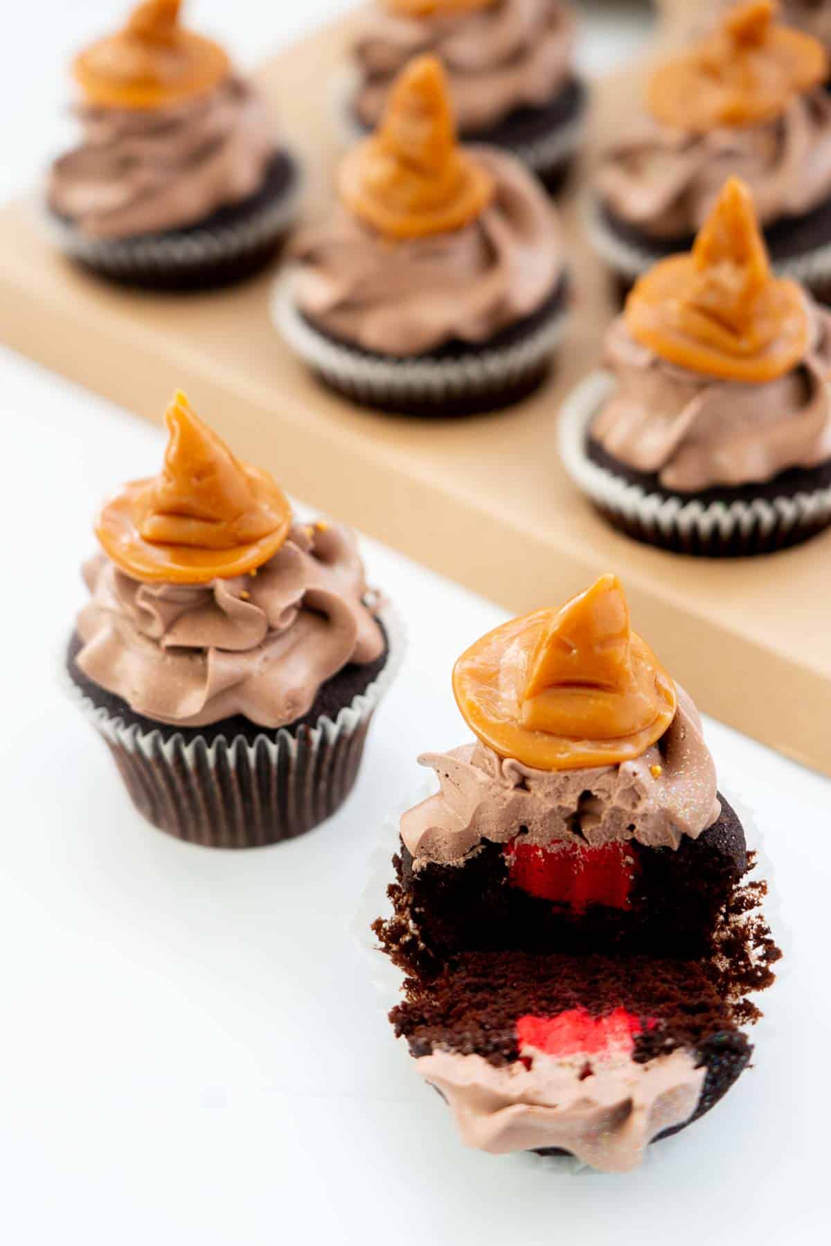 A sorting hat cupcake cut in half to reveal its hidden red butter cream filling.