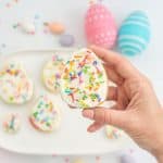 A fruit easter egg being held above a platter of healthy easter eggs.