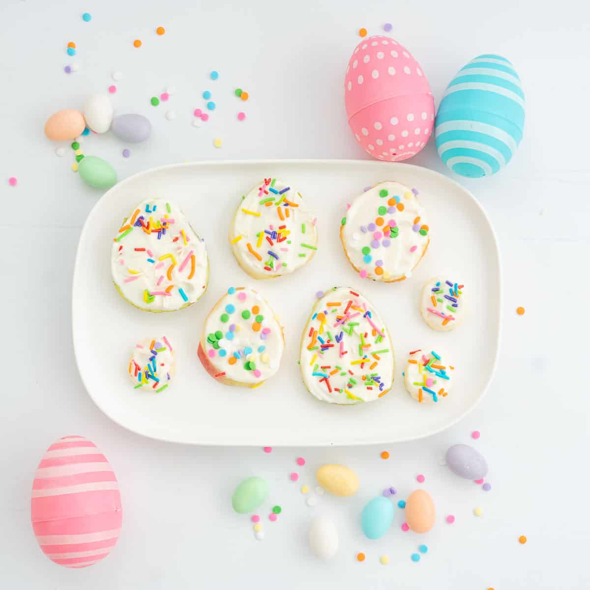 Fruit slice easter eggs on a white rectangular platter, decorated with colourful easter eggs.