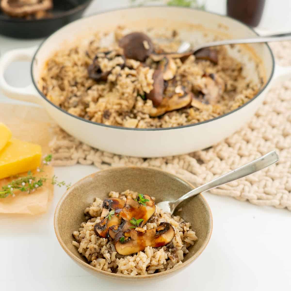 a serving of mushroom risotto on a table with a large dish of risotto.