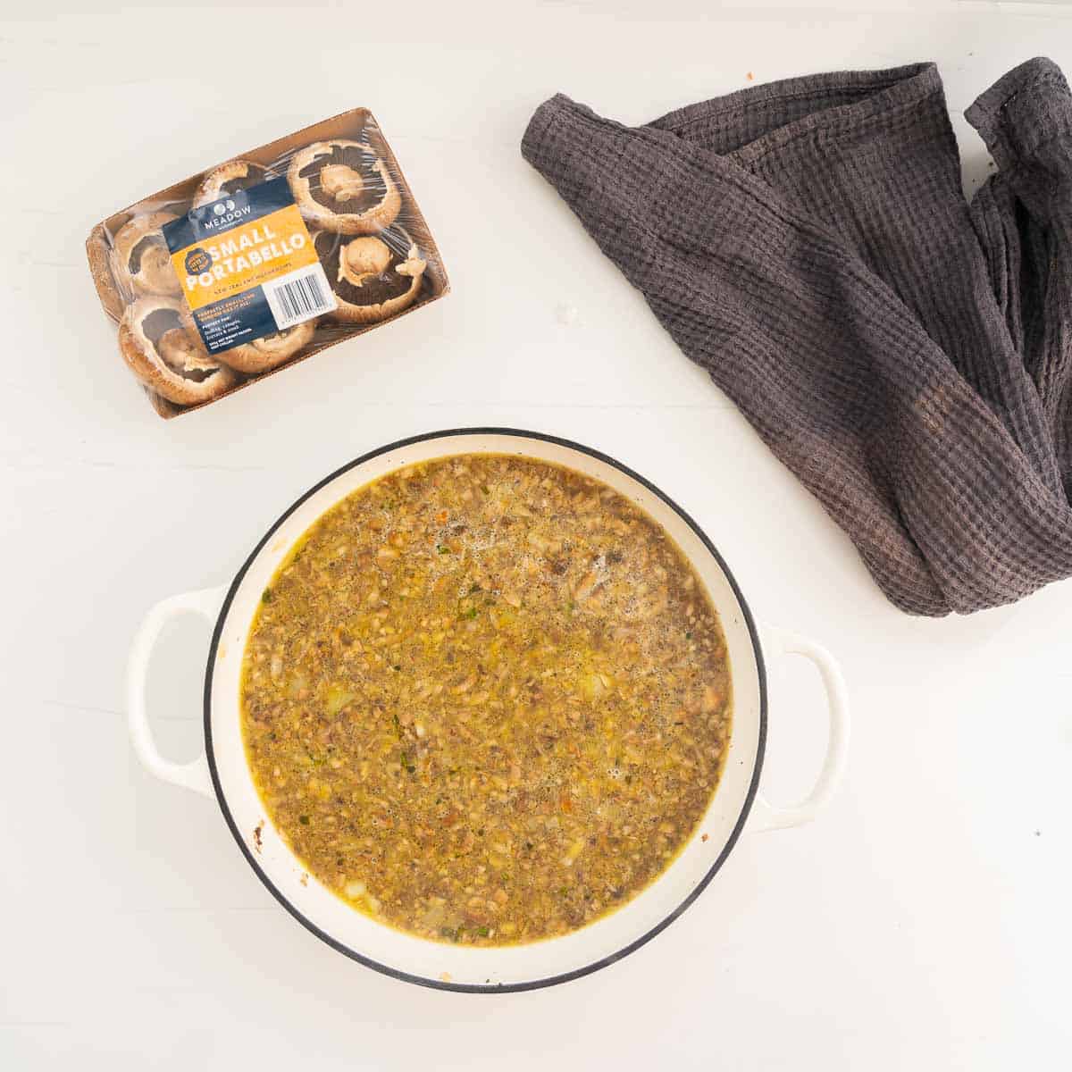 Stock and rice in white enamel cookware.