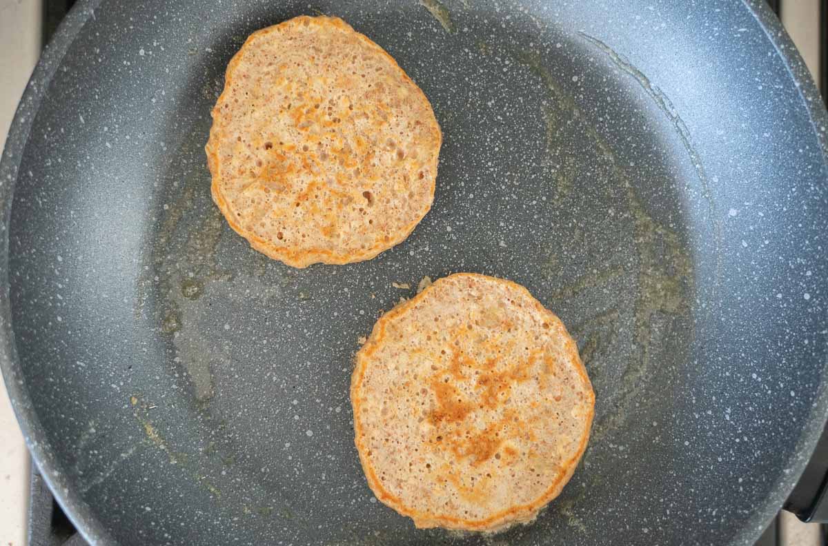 Oat pikelets cooking in a greased fry pan.