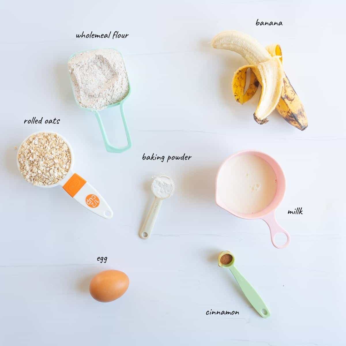 The ingredients to make banana oat pikelets laid out on a bench top with text overlay.